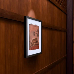 Frame 531 in Dust, gel plate monotype by Daniel Arendzen, framed on a wooden wall under a spotlight, seen from the side, with binoculars, a watch and a lighter on a table below. The room is a Blender render of the interior of the same traditional Malaysian house shown in the print.
