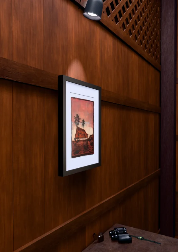 In Pink Sunset, gel plate monotype by Daniel Arendzen, framed on a wooden wall under a spotlight, seen from the side, with binoculars, a watch and a lighter on a table below. The room is a Blender render of the interior of the same traditional Malaysian house shown in the print.